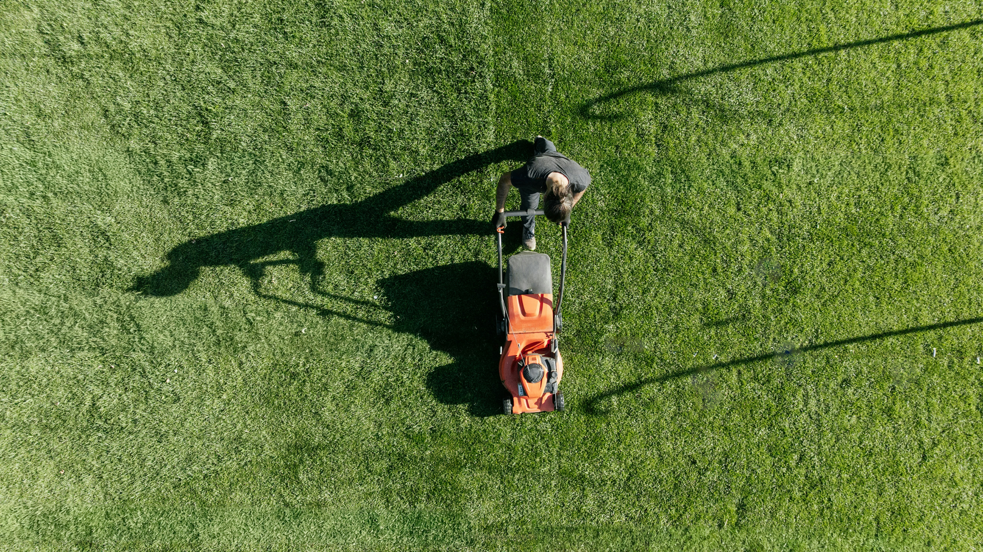 Landscaping professional mowing grass with commercial equipment on a well-maintained property
